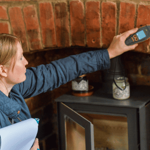 Carys Atkinson, a surveyor, using a damp meter above a brick firepit