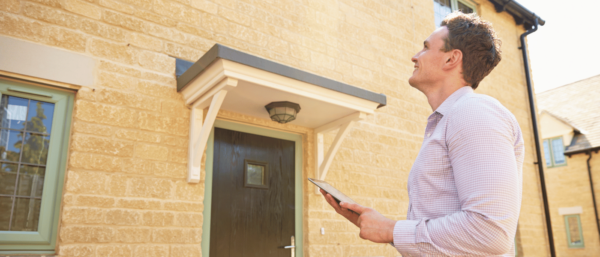 Image shows a valuer assessing a house.