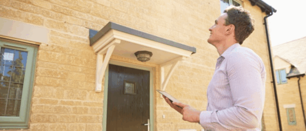 Residential surveyor standing outside a property to carry out a condition survey.