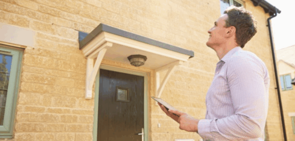 Residential surveyor standing outside a property to carry out a condition survey.